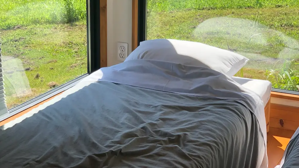 「ザ ノマド 八ヶ岳」のタイニーホテル内のベッド。周りが窓で囲まれていて自然を感じられる